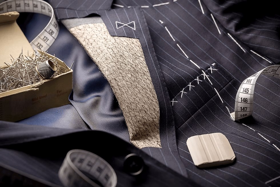Veste rayée en cours de montage : toile d'entoilage, bâti au fil blanc, mètre ruban et craie de tailleur
